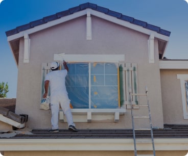 A painter in Byron Bay is painting an exterior wall of a residential property